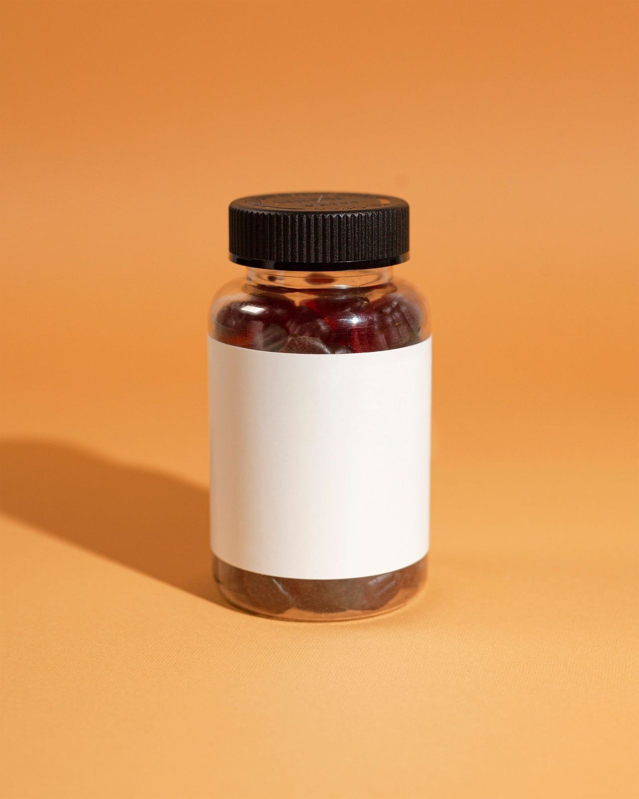 Pote de cápsulas com rótulo em branco sobre fundo laranja