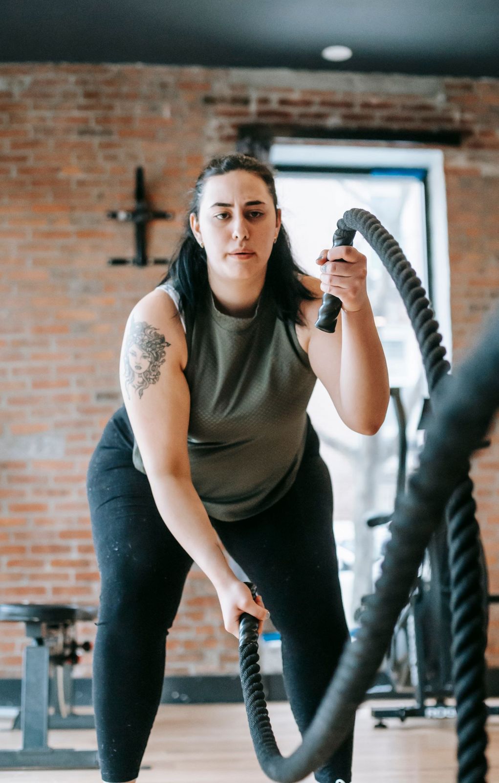 Mulher treinando com corda naval em uma academia